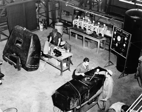 Vintage black and white photograph of men working on fuel tank.