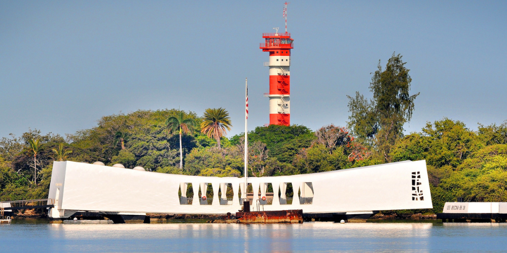 Picture of the USS Arizona memorial with a view of the Ford Island Control Tower behind it.