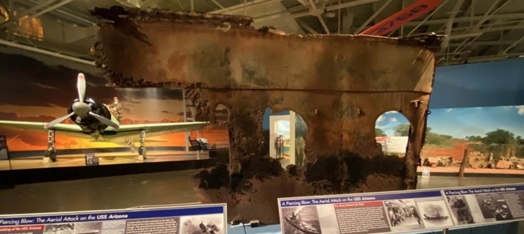 Photograph of a museum exhibit with a piece of the USS Arizona.