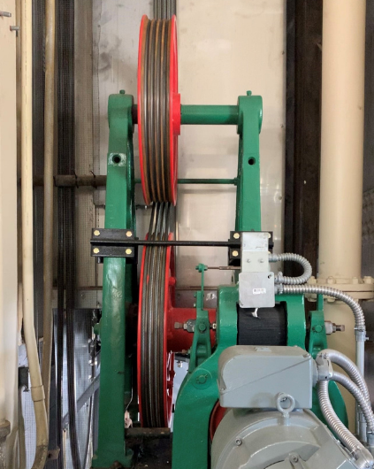 Recent picture of elevator machinary. Belts and pipes are visible.