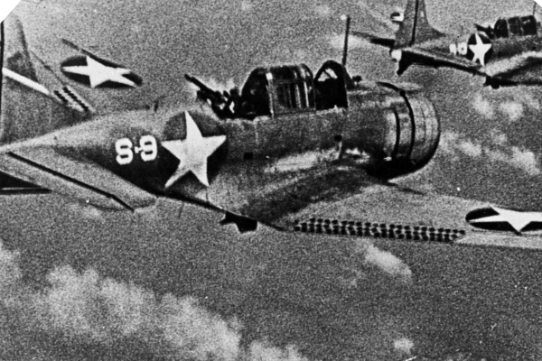 Black and White photograph of the bomber aircraft the Dauntless. A large star adorns the side of the aircraft as it flys above the clouds.