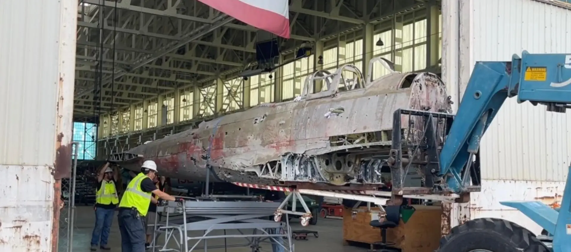 Photograph of WWII aircraft 'Nakajima B5N - Kate' being loaded into hangar to begin restoration at PHAM.