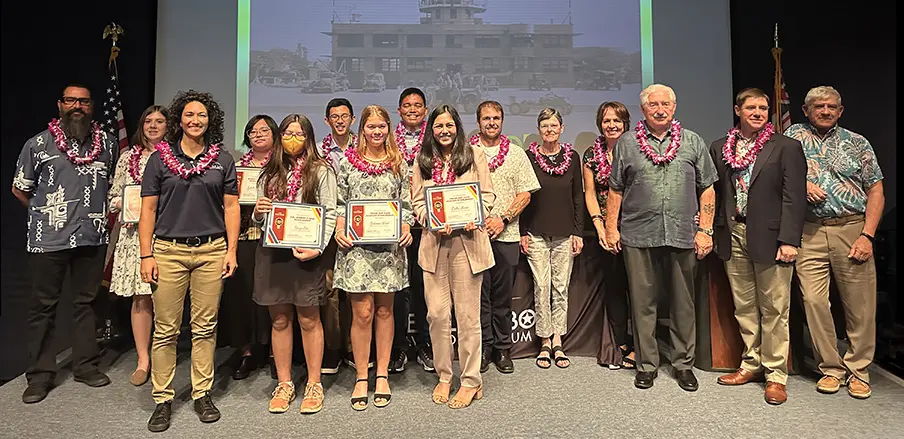 Photograph of 2023 Scholarship Recipients on stage smiling with certificates in hand.