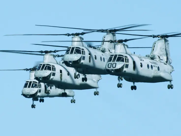 Multiple Boeing Vertol helicopters flying in a clear blue sky.