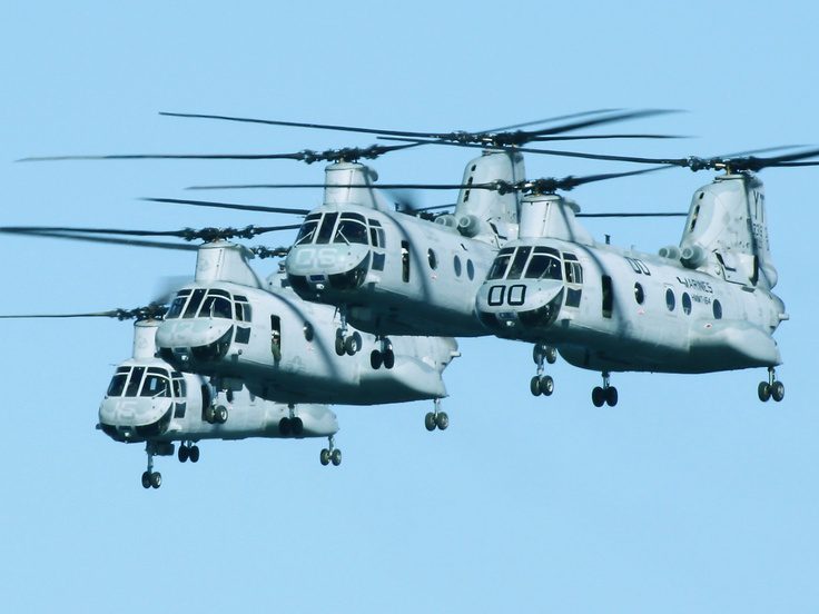 Multiple Boeing Vertol helicopters flying in a clear blue sky.